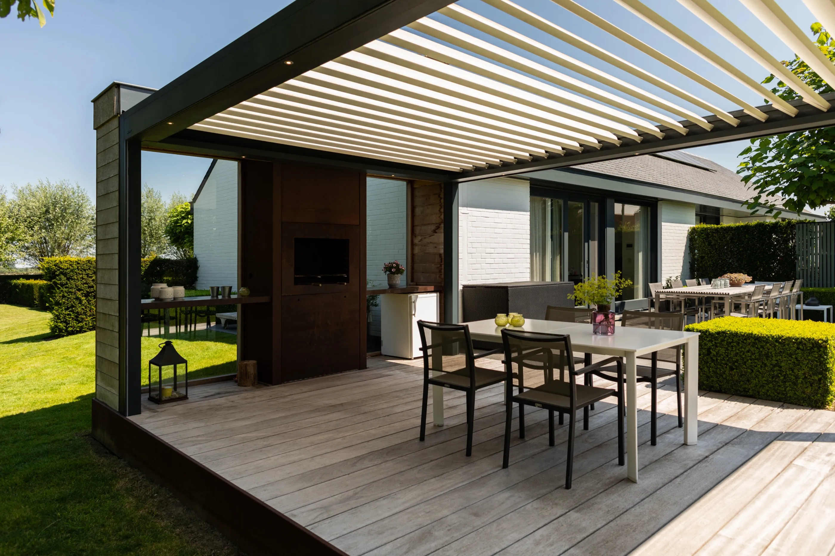 Lamellendach über einer Terrasse mit offenem Übergang zum Garten