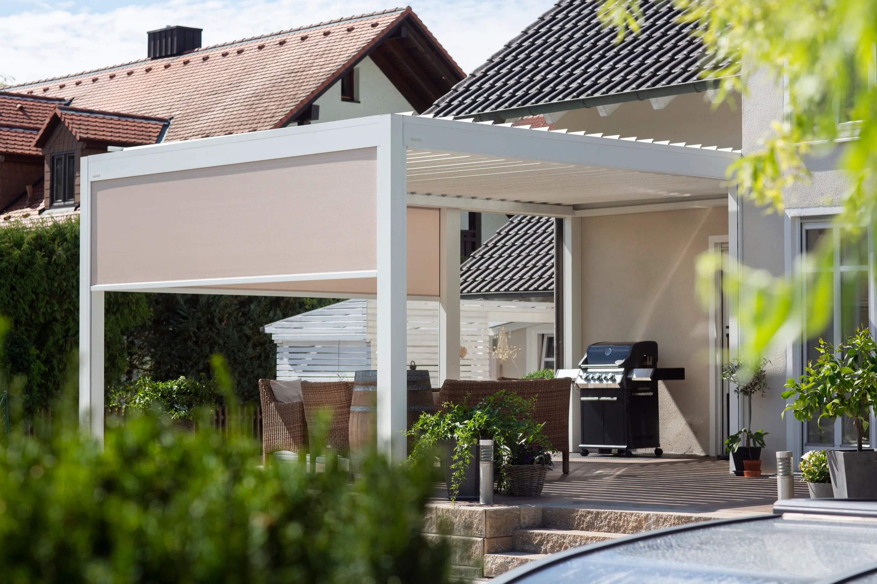 Weißes Lamellendach mit seitlichem Sonnenschutz als Erweiterung einer Terrasse