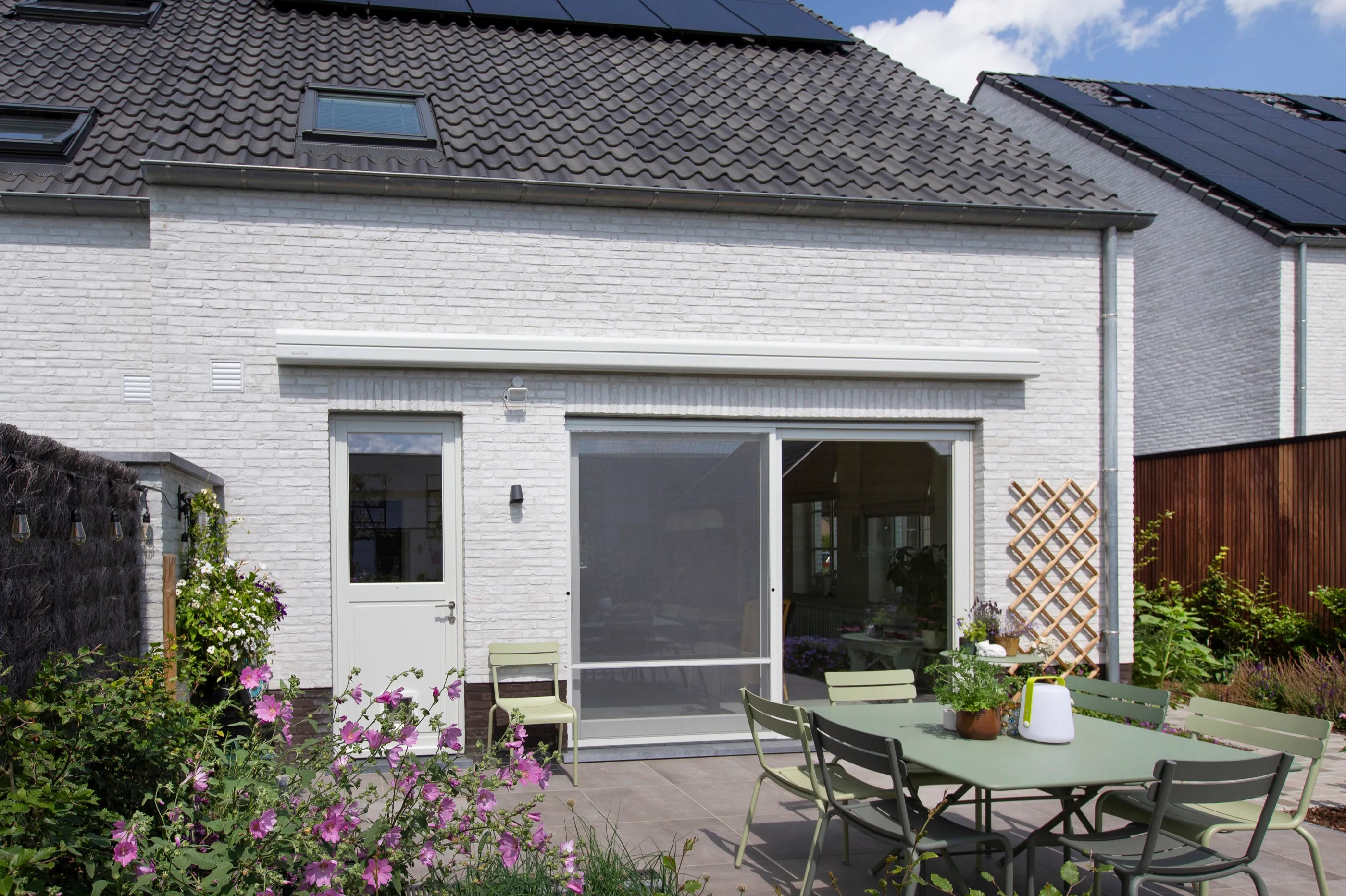 Markise über dem Sitzbereich einer kompakten Gartenterrasse