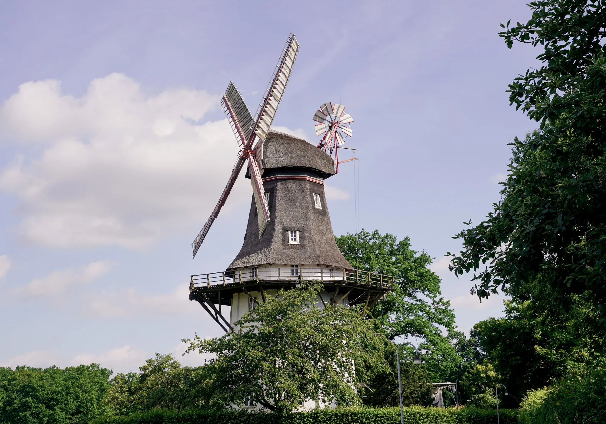 Reetgedeckte Windmühle zwischen grünen Bäumen in Bremen-Oberneuland