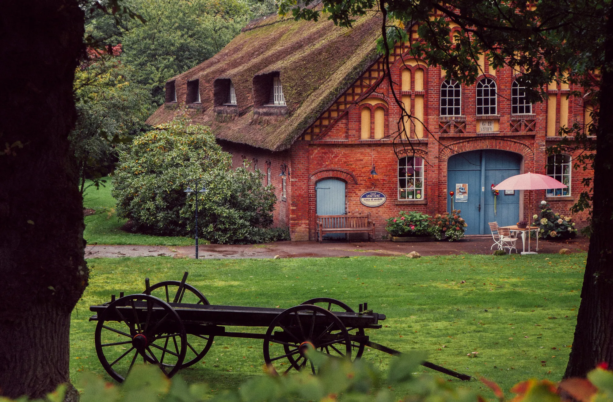 Historisches Fachwerkhaus mit Reetdach und einem alten Holzwagen im Garten in Worpswede